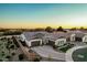 A sprawling single-story home showcases a three-car garage and beautiful desert landscaping at dusk at 4247 E Tonto Pl, Chandler, AZ 85249