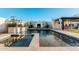 Stunning backyard with a sparkling pool, waterfall feature, cozy fireplace, and a convenient outdoor bar area at 4247 E Tonto Pl, Chandler, AZ 85249