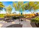 Backyard features a rock garden, patio with dining table, mature trees, and cactus at 5313 N Dakota Dr, Eloy, AZ 85131