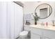 Well-lit bathroom featuring a round mirror, storage basket, and patterned hand towel at 7018 S 41St Pl, Phoenix, AZ 85042