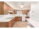 Functional kitchen features wood cabinets, vinyl flooring and laminate counters with white appliances at 715 N 65Th Pl, Mesa, AZ 85205