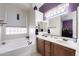 Bathroom featuring a large tub, double sinks, vanity, large mirror, and privacy window at 7232 E Nance St, Mesa, AZ 85207