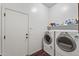 Well-lit laundry room featuring a side-by-side washer and dryer, plus overhead storage shelf at 7232 E Nance St, Mesa, AZ 85207