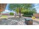 Spacious backyard with a landscaped area, hardscape patio, and a shade tree at 9401 W Raintree Dr, Sun City, AZ 85351