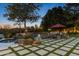 Backyard at dusk showcases a patio seating area and artificial turf squares, and pool with rock waterfall at 10800 E Cactus Rd # 38, Scottsdale, AZ 85259