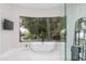 A bathtub sits beneath a large window offering views of the greenery and pool at 10800 E Cactus Rd # 38, Scottsdale, AZ 85259