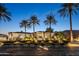 Exterior front view of a sprawling luxury home framed by mature palm trees at twilight at 10800 E Cactus Rd # 38, Scottsdale, AZ 85259