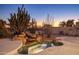 Backyard oasis at twilight with a rock waterfall feature, desert cacti, and a tranquil ambiance at 11627 E Bella Vista Dr, Scottsdale, AZ 85259