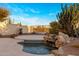 Backyard oasis with a stone waterfall feature, tiled pool, desert plants, and scenic views at 11627 E Bella Vista Dr, Scottsdale, AZ 85259