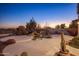 Charming backyard with a rock water feature surrounded by desert landscaping at dusk at 11627 E Bella Vista Dr, Scottsdale, AZ 85259