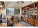 Inviting office with a large wooden bookcase, a comfortable chair, and a view of the outdoor greenery at 11627 E Bella Vista Dr, Scottsdale, AZ 85259