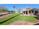 Expansive backyard featuring lush green grass, decorative landscaping, and a covered patio with outdoor seating at 12439 W Monte Vista Rd, Avondale, AZ 85392