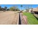 View of grassy backyard that is lined by desert landscaping on the opposite side of the fence at 12439 W Monte Vista Rd, Avondale, AZ 85392