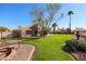 Spacious backyard showcasing manicured lawn, mature trees, and a covered patio at 12439 W Monte Vista Rd, Avondale, AZ 85392