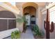 Arched doorway with white door, sidelights, and desert landscaping featuring palm trees and cacti at 12439 W Monte Vista Rd, Avondale, AZ 85392