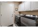 Laundry room with white cabinets and stainless steel washer and dryer at 12439 W Monte Vista Rd, Avondale, AZ 85392