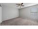 This bedroom includes a ceiling fan, neutral walls and carpet, and a window for natural light at 13569 W Ventura St, Surprise, AZ 85379