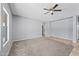 Spacious living room featuring neutral gray walls, plush carpeting, and a modern ceiling fan at 13569 W Ventura St, Surprise, AZ 85379