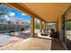 Covered patio with lounge area overlooks the sparkling pool and well-manicured yard at 13569 W Ventura St, Surprise, AZ 85379