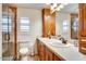 Bathroom with double sinks, wood cabinets, toilet, and a glass-enclosed shower at 1489 Thrasher Ln, Wickenburg, AZ 85390