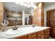 Bright bathroom featuring double sinks, wood cabinets, a walk-in shower, and a large mirror at 1489 Thrasher Ln, Wickenburg, AZ 85390