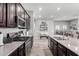 Spacious kitchen showcasing stainless steel appliances, dark cabinets, and an island with a view into the dining area at 16561 W Cielo Grande Ave, Surprise, AZ 85387