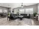 Bright living room featuring a large gray sectional, wood-look floors, and a view into the dining area at 16561 W Cielo Grande Ave, Surprise, AZ 85387