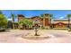 Charming clubhouse with brick driveway, fountain, arched entryway, and lush palm trees in a luxurious community at 20151 N Riverbank Rd, Maricopa, AZ 85138