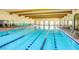 Well lit indoor lap pool featuring exposed beam ceilings and large arched windows at 20151 N Riverbank Rd, Maricopa, AZ 85138