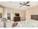 Well-lit main bedroom with a chaise lounge, TV, and neutral-colored walls at 20151 N Riverbank Rd, Maricopa, AZ 85138