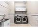 Well-organized laundry room with modern washer and dryer, sink, tiled walls, and overhead storage at 22426 N 29Th Pl, Phoenix, AZ 85050