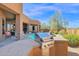 Built-in outdoor kitchen and bbq area with seating overlooking pool and desert landscape at 35345 N Canyon Creek Ct, Carefree, AZ 85377