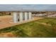 Aerial view of four tall silos in a green space, surrounded by homes and distant mountains under a bright, cloudy sky at 3744 E Sierra Madre Ave, Gilbert, AZ 85296