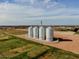 Aerial view of four tall silos in a grassy field near a neighborhood, under a bright, cloudy sky at 3744 E Sierra Madre Ave, Gilbert, AZ 85296