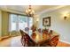 A dining room with wood floors, a wooden table with eight chairs, and natural light from a large window at 3744 E Sierra Madre Ave, Gilbert, AZ 85296