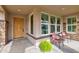 Charming front porch featuring stone accents, an elegant wooden front door, and cozy seating area at 3744 E Sierra Madre Ave, Gilbert, AZ 85296