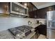 Close-up of a stainless steel gas range and microwave above the stove, paired with granite counters and dark wood cabinets at 5844 S Tobin --, Mesa, AZ 85212