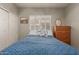 Bedroom with a comfortable bed, natural light from shuttered windows, and a wooden dresser at 6834 S Dennis Dr, Tempe, AZ 85283