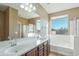 Bright bathroom featuring double sinks, a large mirror, tub, and a shower for a spa-like experience at 7355 W Red Hawk Dr, Peoria, AZ 85383