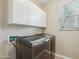 Well-lit laundry room with front load washer and dryer, overhead cabinets, and tile flooring at 7355 W Red Hawk Dr, Peoria, AZ 85383