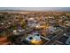 Sunset aerial view of a quiet neighborhood with well-maintained homes, lush landscaping, and city lights in the distance at 8443 E Sheridan St, Scottsdale, AZ 85257