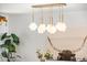 A modern dining room with a geometric chandelier, Monstera plant, and artwork at 8443 E Sheridan St, Scottsdale, AZ 85257