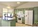 Well-lit kitchen featuring stylish green cabinets, white appliances, and granite countertops for a modern feel at 9238 W Behrend Dr, Peoria, AZ 85382