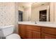 Cozy bathroom with wood cabinets, classic floral wallpaper, and a large mirror creating a bright and inviting space at 10901 E Sunnydale Dr, Sun Lakes, AZ 85248