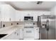 A modern white kitchen with stainless steel appliances, black hardware, and a black and white tiled backsplash at 1119 W Heather Ave, Gilbert, AZ 85233