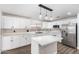 A modern white kitchen with a center island, stainless steel refrigerator, black hardware, and decorative pendant lights at 1119 W Heather Ave, Gilbert, AZ 85233