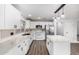 A modern white kitchen with a center island, stainless steel refrigerator, black hardware, and stainless steel appliances at 1119 W Heather Ave, Gilbert, AZ 85233