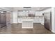 A modern white kitchen with a center island, stainless steel refrigerator, black hardware, and black and white backsplash at 1119 W Heather Ave, Gilbert, AZ 85233