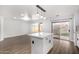 View of the living room with wood floors next to a modern white kitchen with a center island and black hardware at 1119 W Heather Ave, Gilbert, AZ 85233