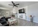 Bright living room with modern ceiling fan, open to kitchen, gray floors, and sleek, modern white storage cabinet at 12010 N 113Th Ave, Youngtown, AZ 85363